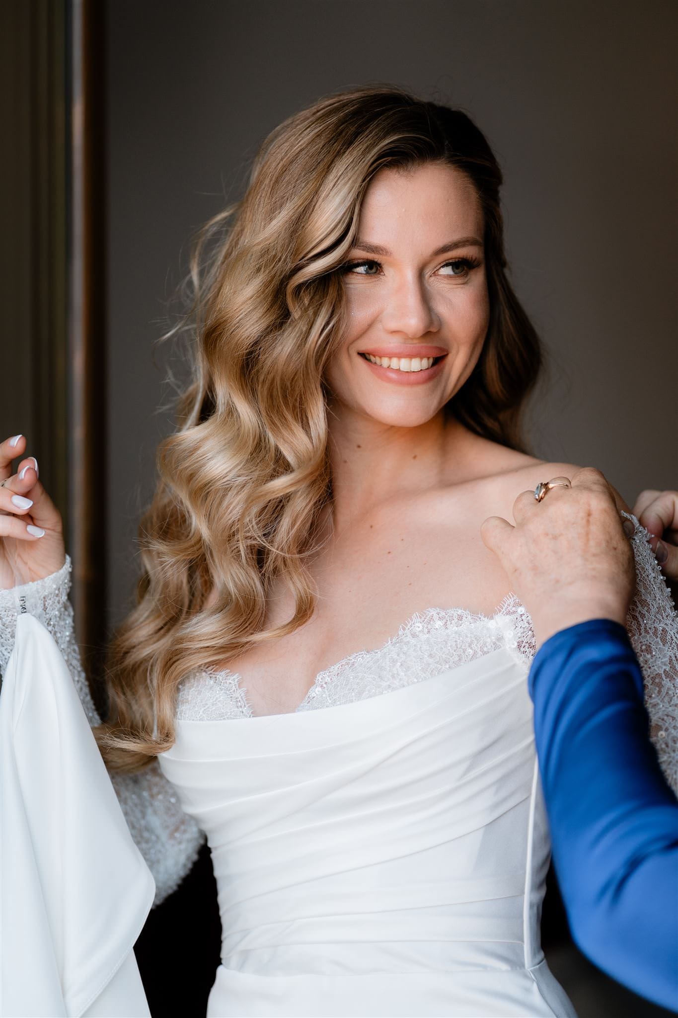 La sposa a Verona si prepara a indossare l'abito da cerimonia. Un momento solenne e ricco di emozioni che il fotografo di matrimoni cattura in ogni dettaglio.
