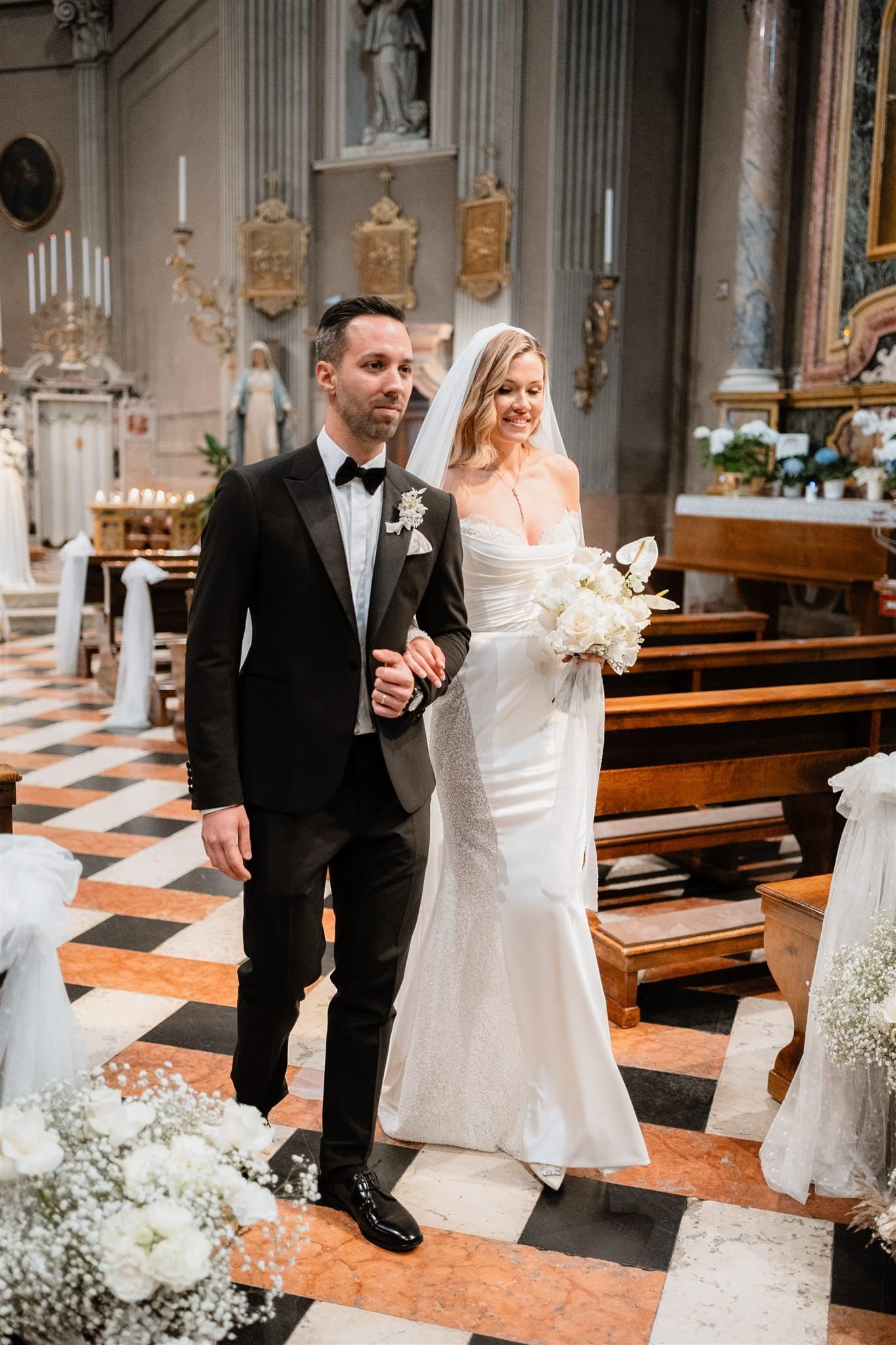 Dopo la cerimonia, gli sposi si dirigono verso l'uscita della chiesa a Verona, mano nella mano. Il fotografo cattura questo momento di gioia, mentre i due sposi iniziano ufficialmente la loro vita insieme.