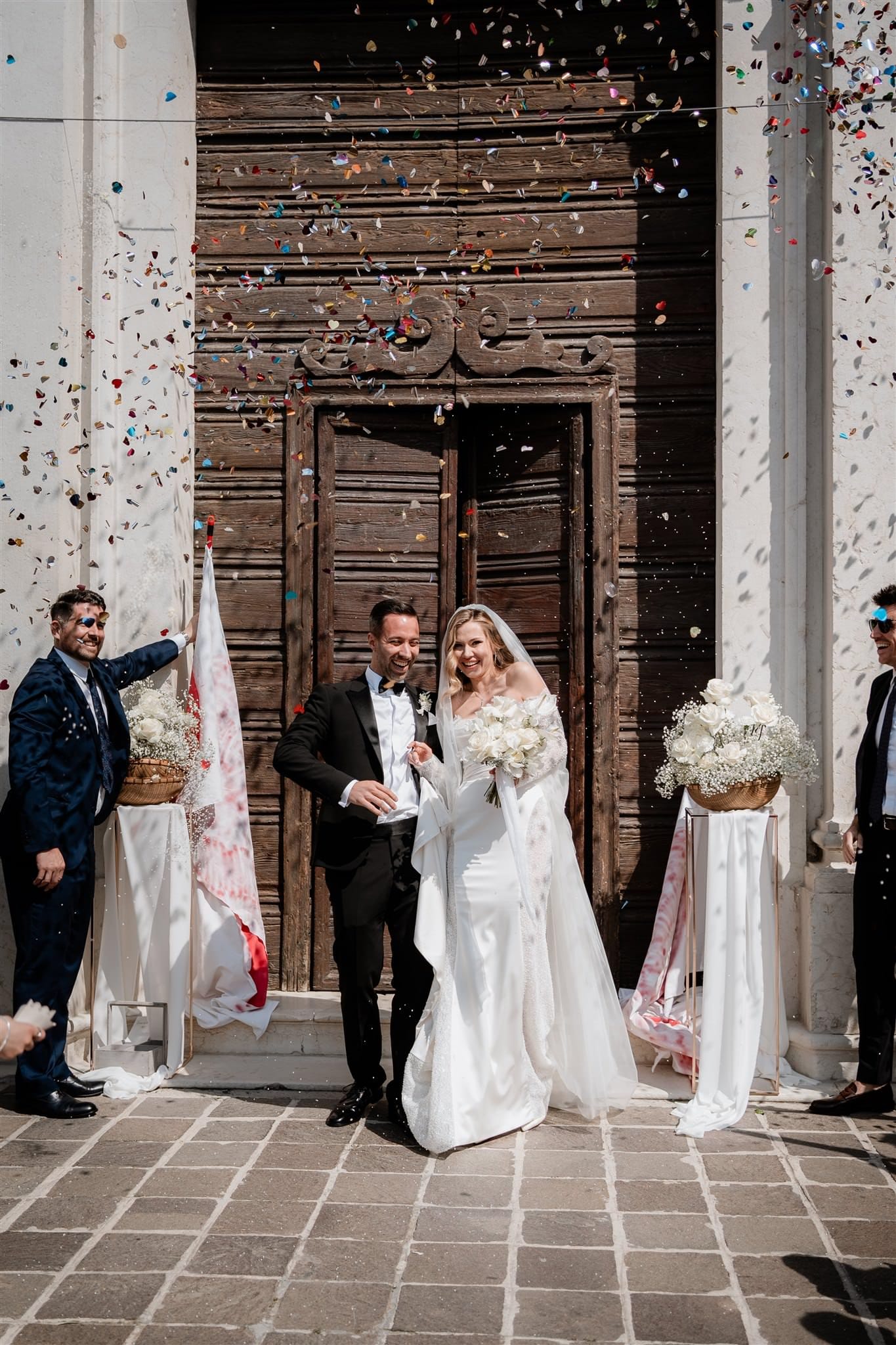 Gli sposi a Verona sorridono mentre vengono accolti con il lancio del riso. Un momento di grande emozione, dove la gioia della coppia si mescola alla festa degli amici e dei parenti, creando ricordi indimenticabili da custodire per sempre.