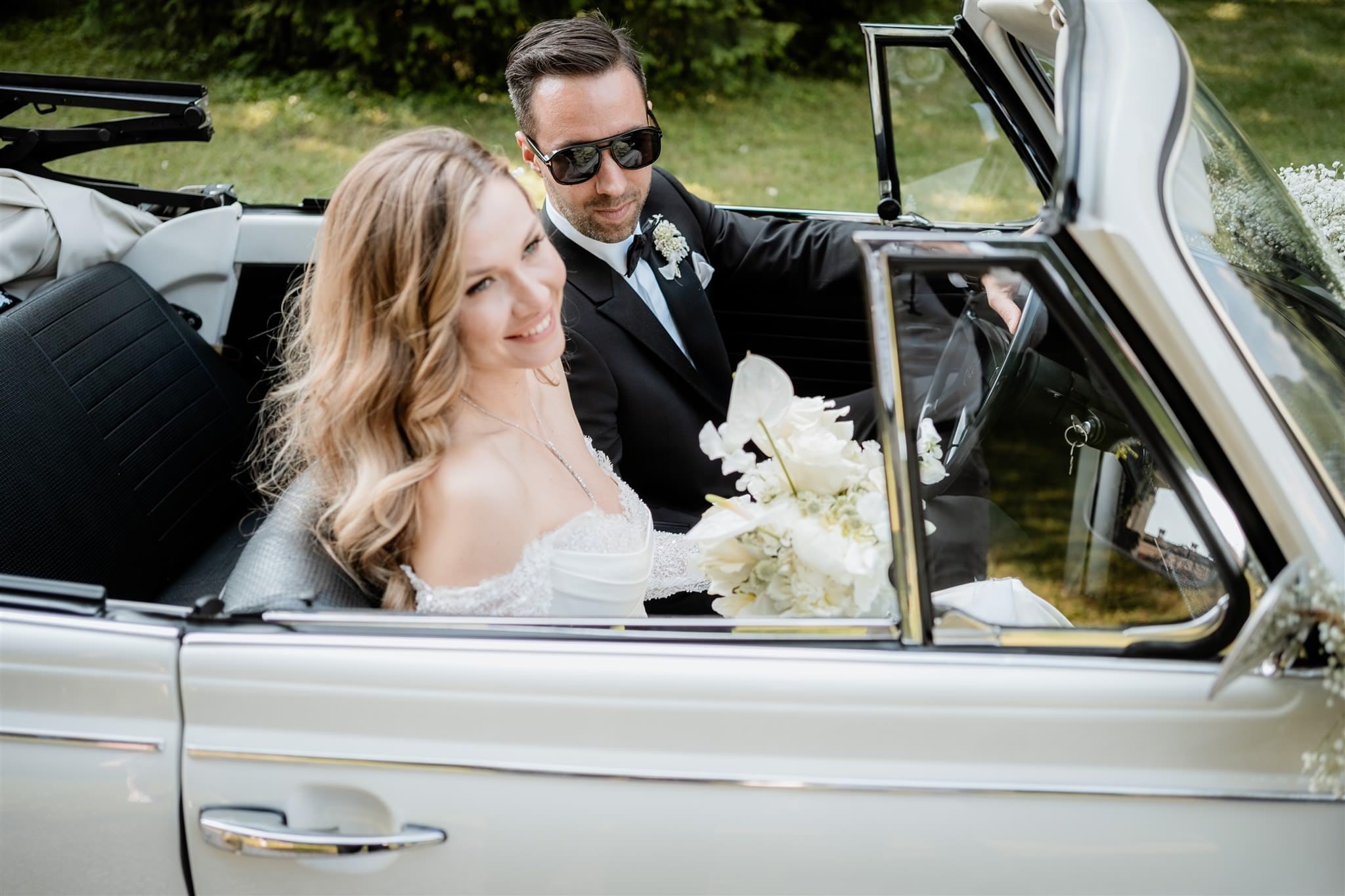 Gli sposi nella loro auto nuziale salutano e sorridono agli invitati