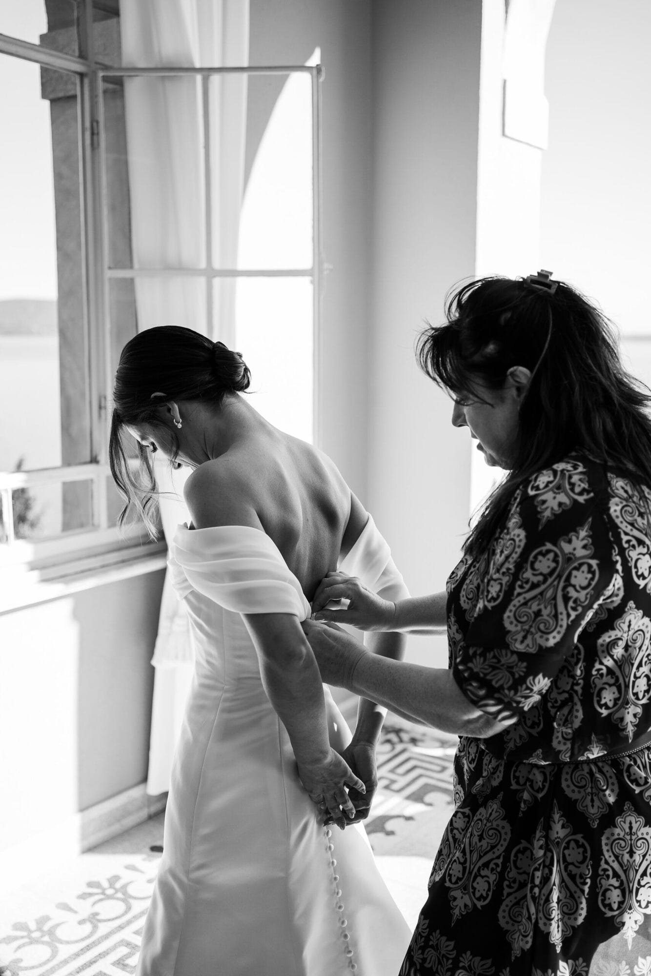 In una stanza piena di luce naturale, la sposa si dedica con calma alla sua preparazione, ogni dettaglio perfettamente curato. La vista sul lago rende questo momento ancora più speciale e romantico.