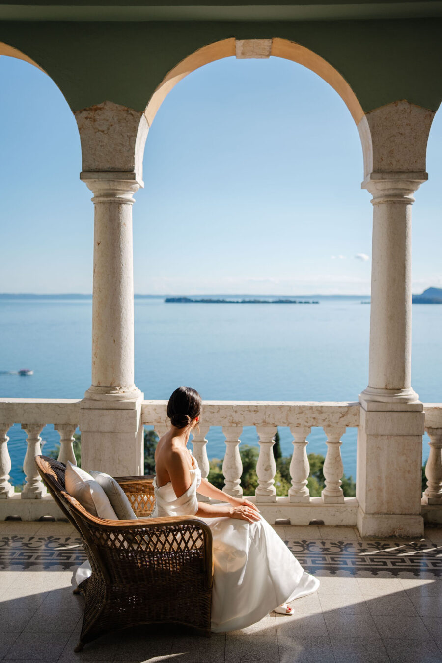 Con il Lago di Garda che si staglia sullo sfondo, la sposa si prepara con calma ed eleganza, ogni gesto un riflesso di amore e di attesa per il giorno che sta per arrivare.