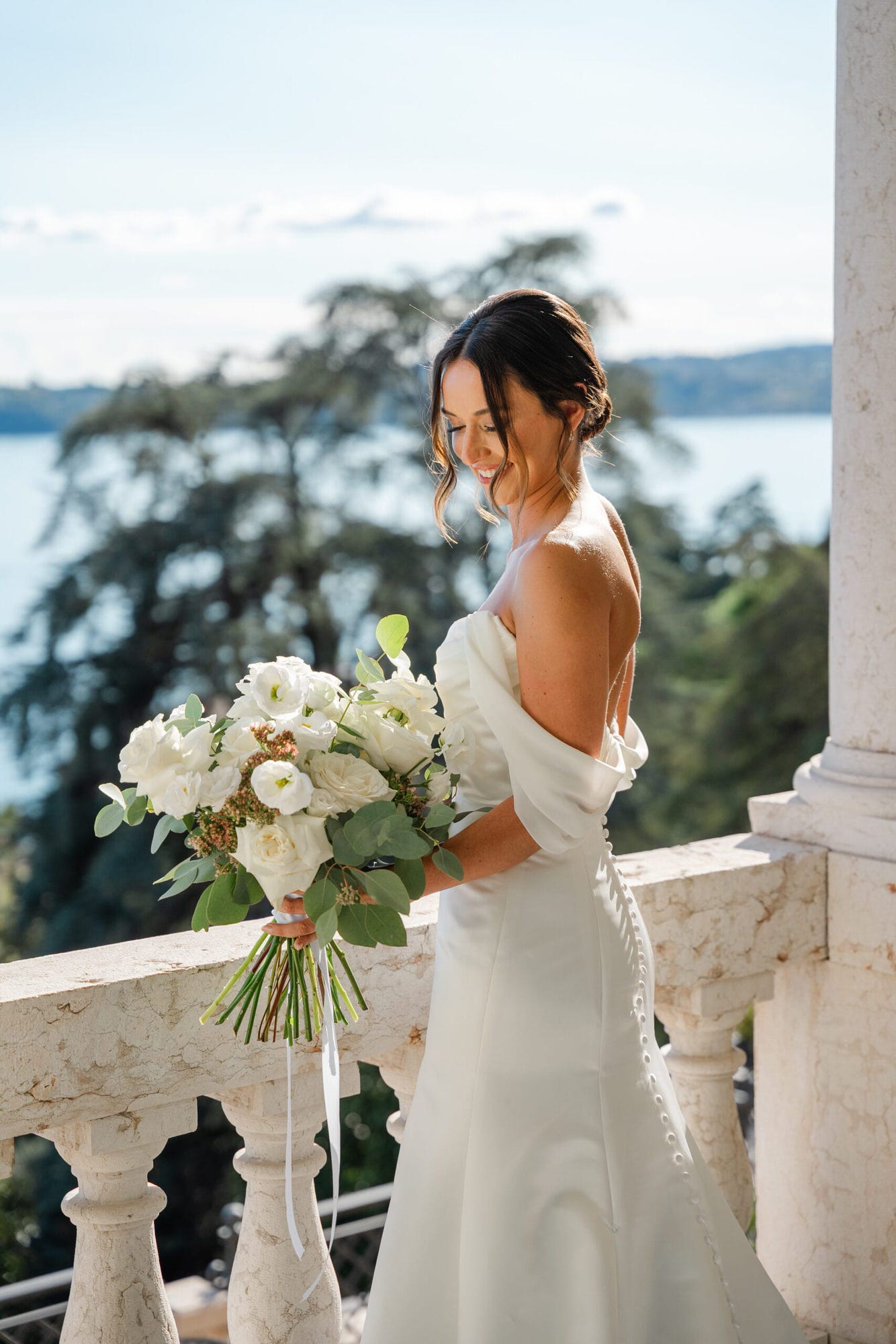 La sposa si prepara nella sua stanza con vista sul Lago di Garda. Ogni dettaglio, dal suo abito impeccabile agli accessori, è curato con amore, mentre la luce naturale che entra dalla finestra rende questo momento ancora più magico.