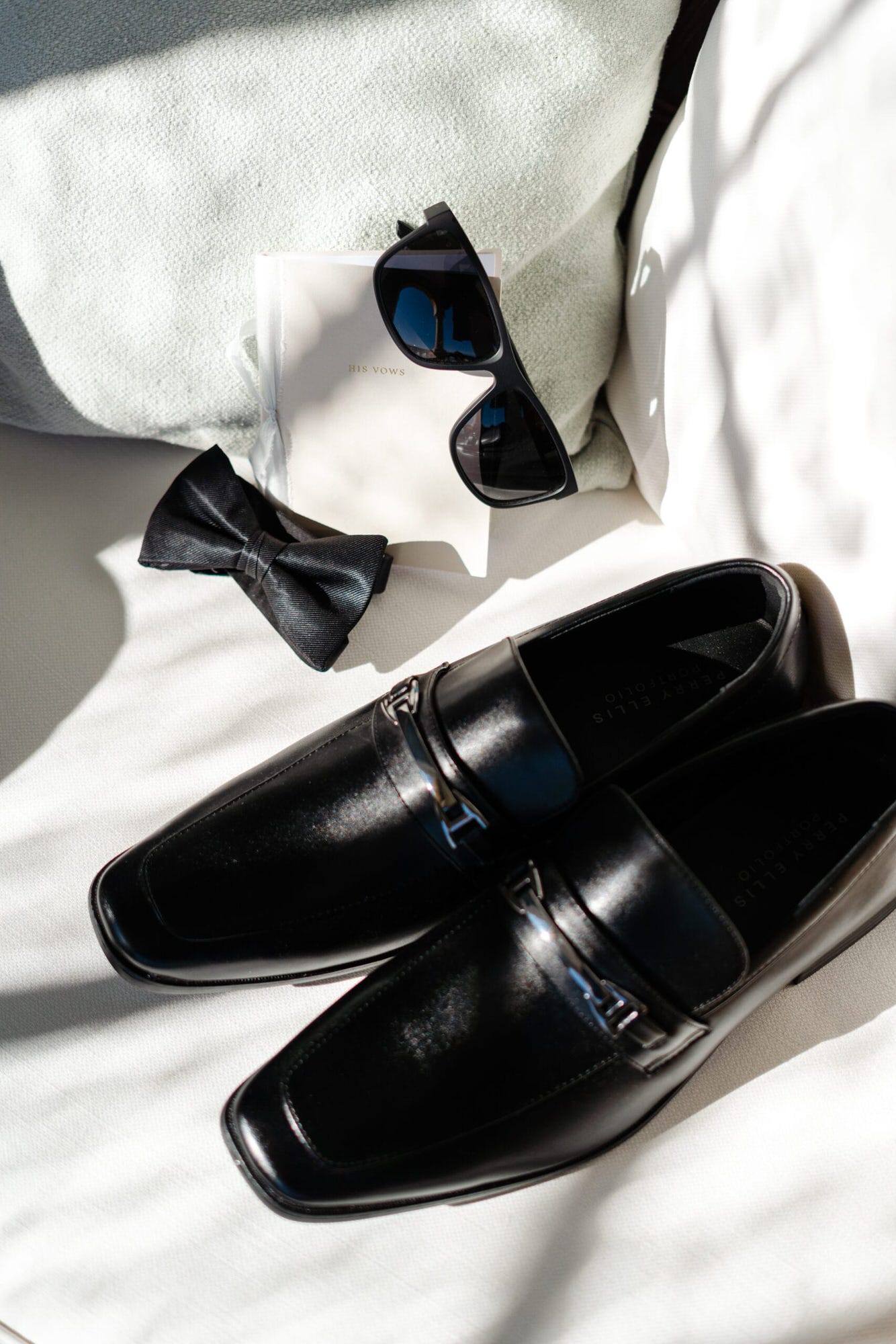 Una fotografia degli accessori dello sposo tra cui: occhiali, scarpe e papillon