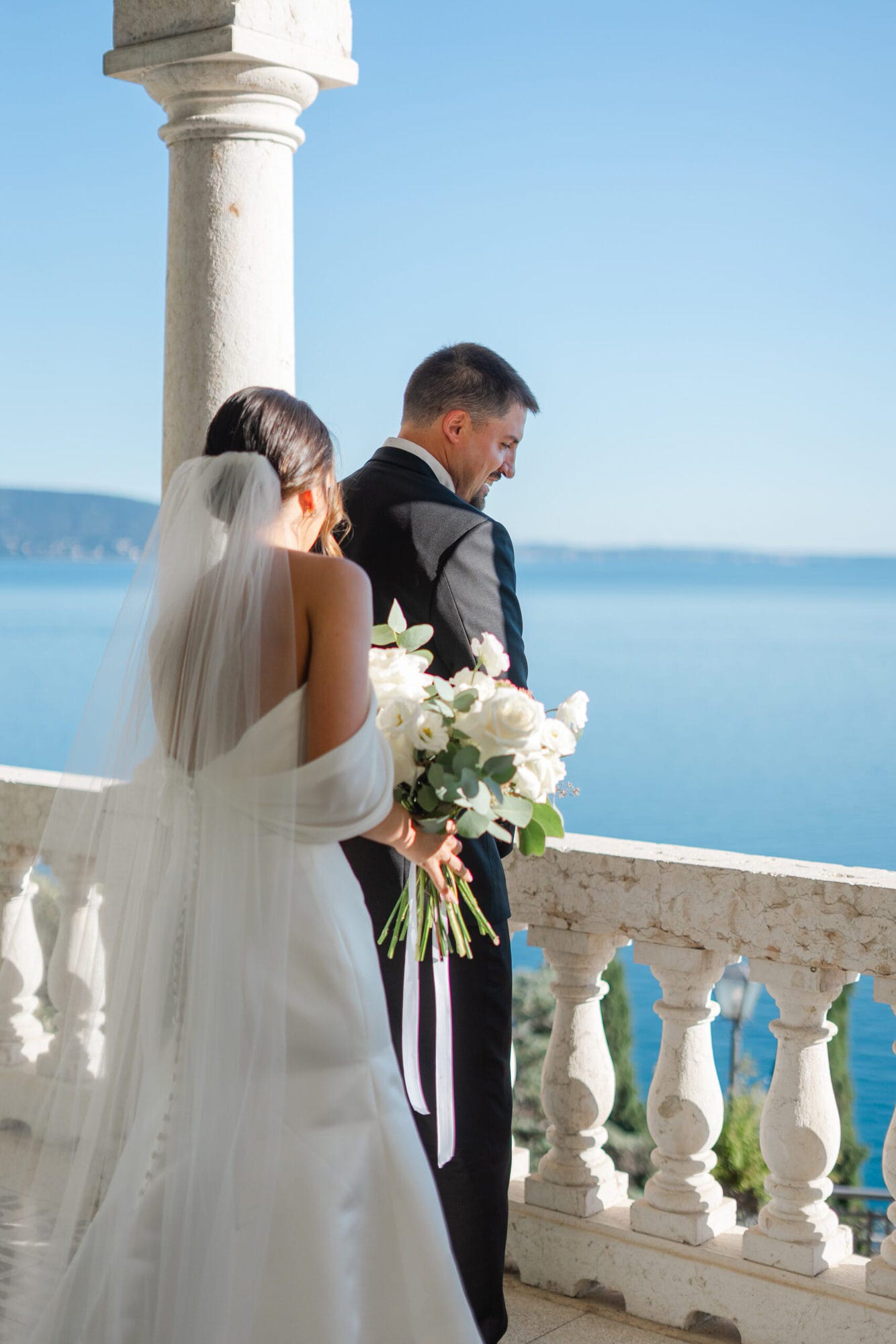 Con la vista sul Lago di Garda, lo sposo aspetta in silenzio, emozionato, il momento del first look. L'atmosfera è carica di aspettativa, e il suo profilo, mentre si trova di spalle, trasmette tutta la profondità di un momento che segnerà la giornata.
