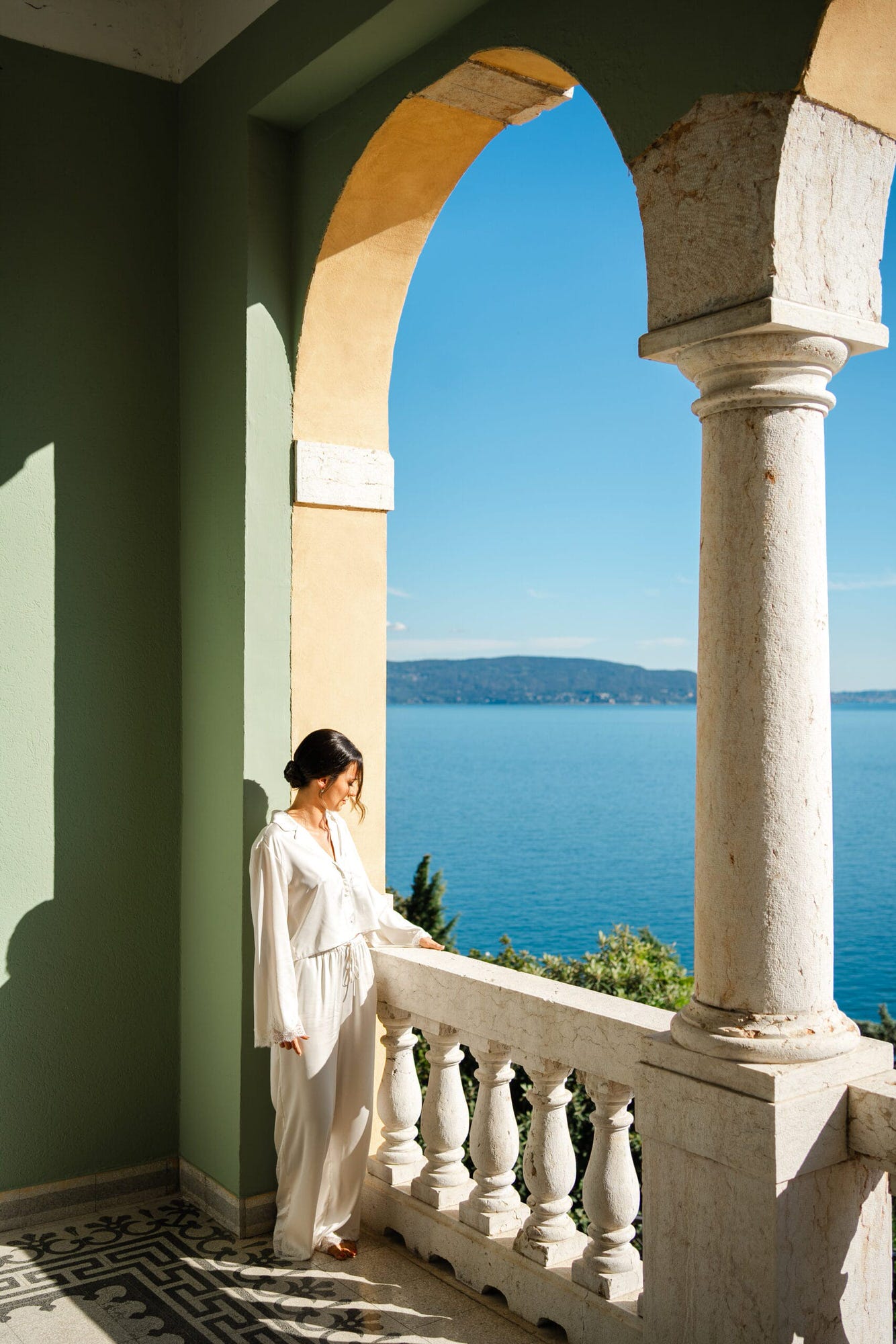 Mentre la sposa si veste, i dettagli finali del suo abito e accessori sono catturati in scatti che parlano di eleganza e delicatezza. La terrazza con vista sul lago offre il contesto perfetto per immortalare questa magia.