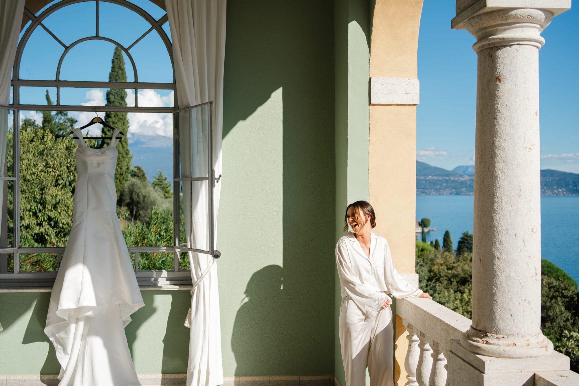 Mentre la sposa si veste, i dettagli finali del suo abito e accessori sono catturati in scatti che parlano di eleganza e delicatezza. La terrazza con vista sul lago offre il contesto perfetto per immortalare questa magia.