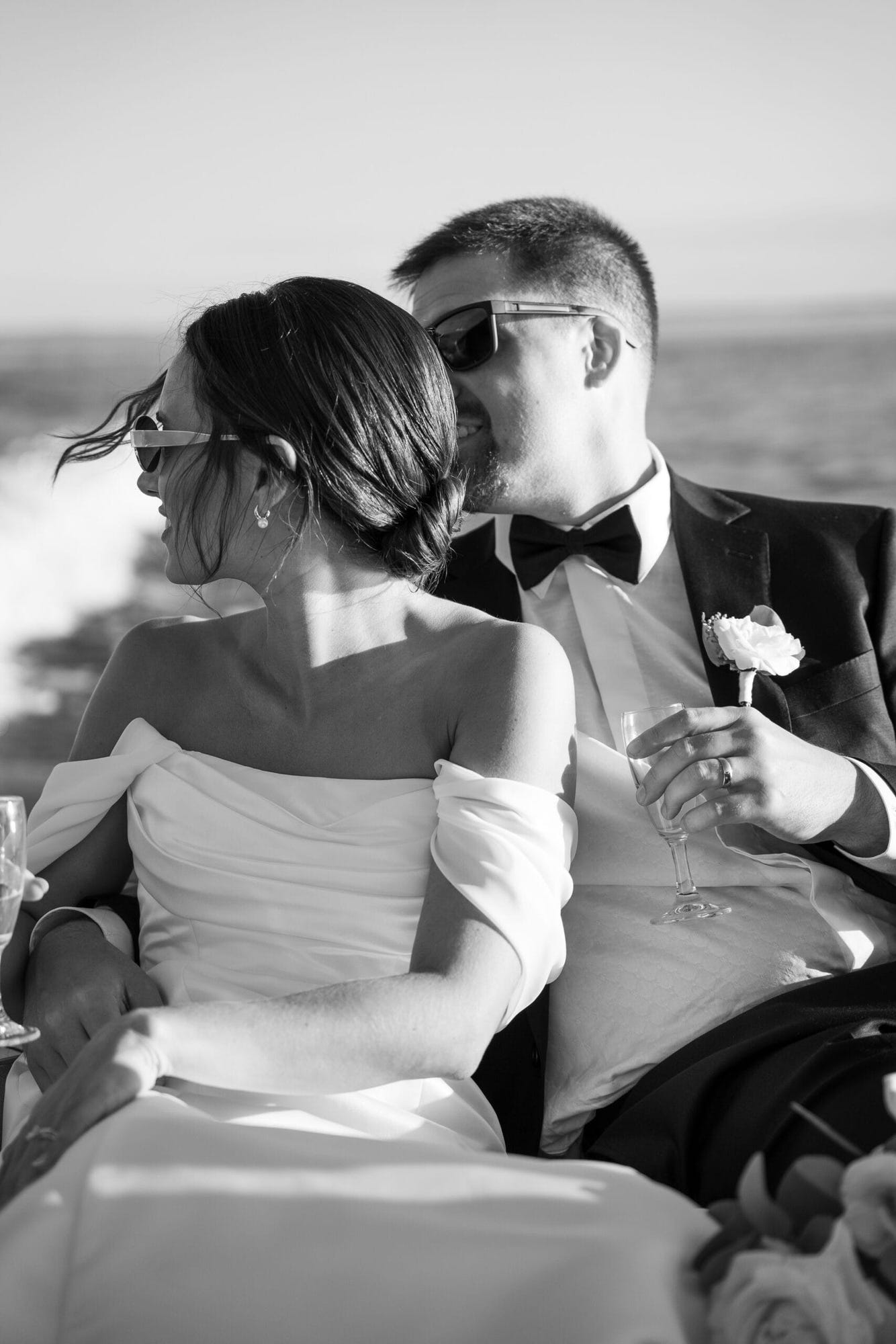 Bianco e nero di un abbraccio a bordo, mentre il vento scompiglia i capelli della sposa