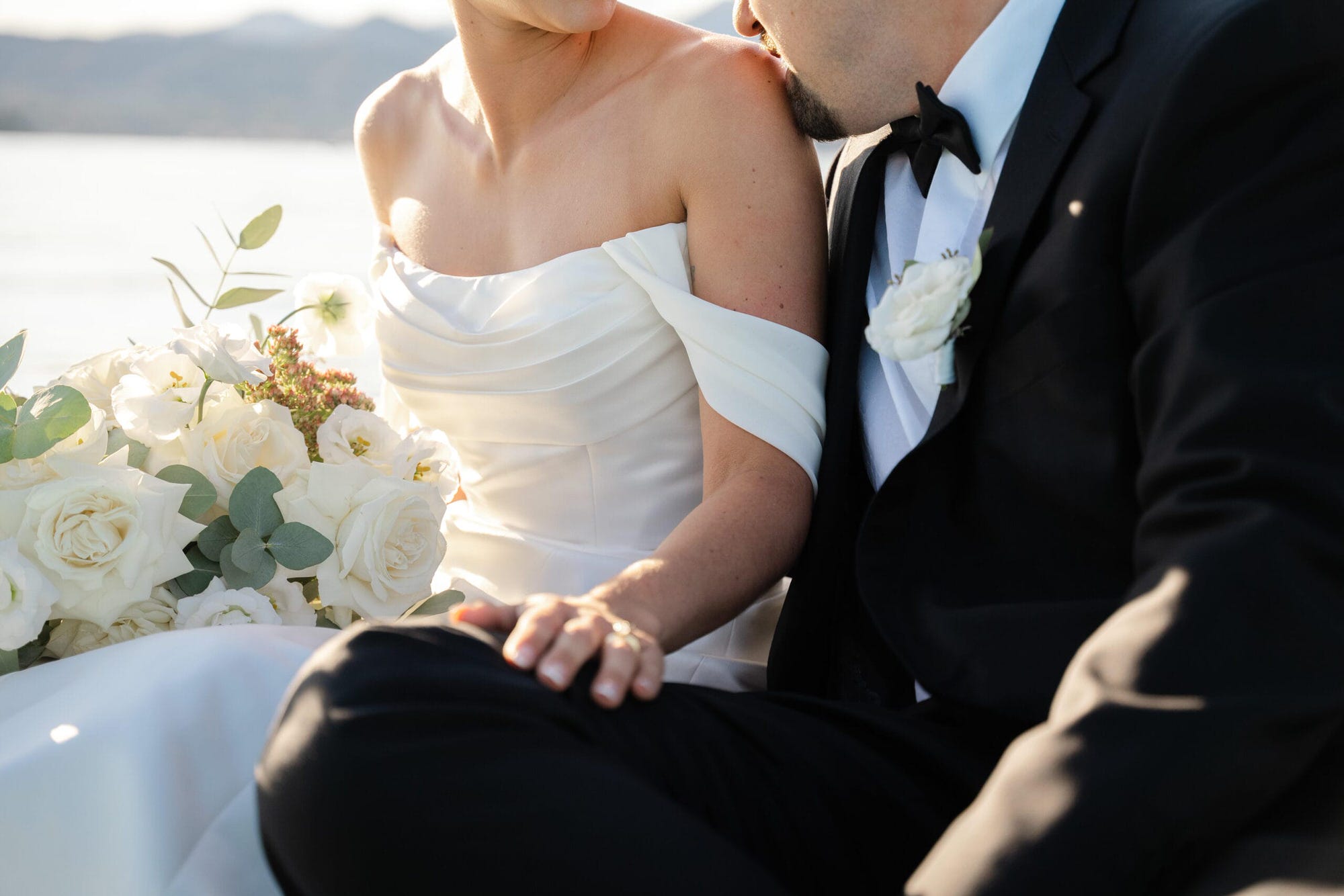 Gli sposi abbracciati a bordo della barca, con il vento tra i capelli della sposa