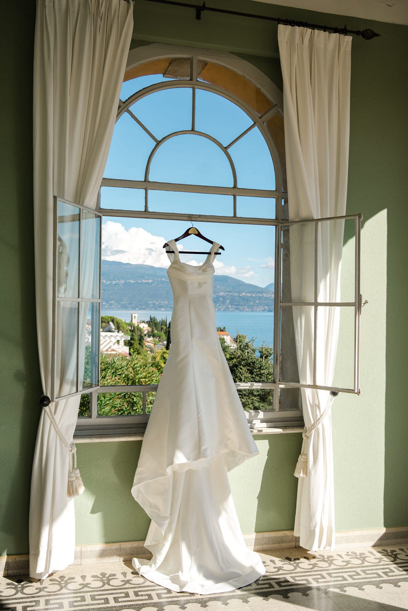 Una foto del vestito sposa appeso, con il lago di garda che fa da sfondo
