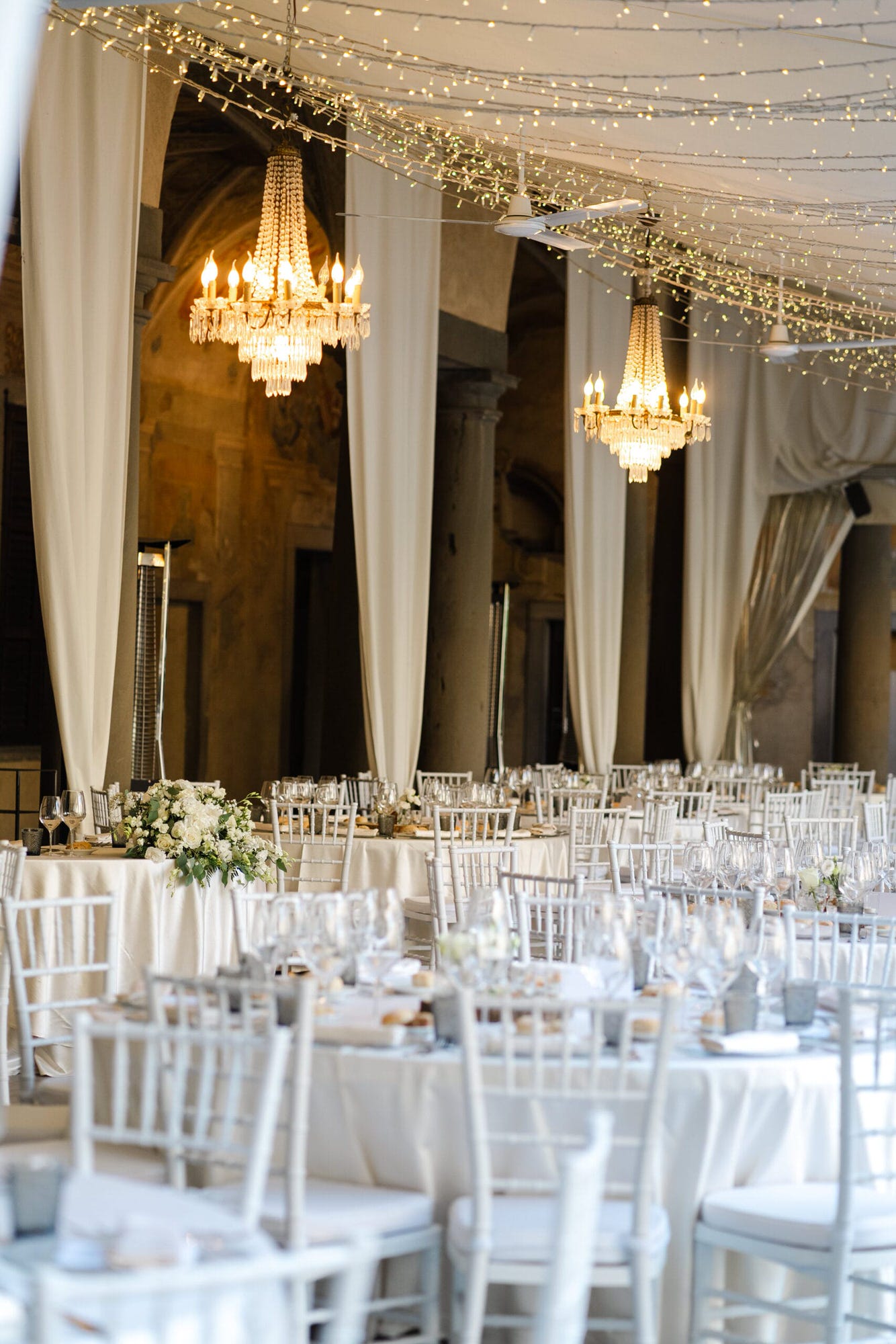 Un'immagine elegante della cena del matrimonio al Castello di Cavernago, Bergamo, dove gli sposi e gli invitati si deliziano con piatti prelibati, immersi nell'atmosfera romantica e raffinata della location.