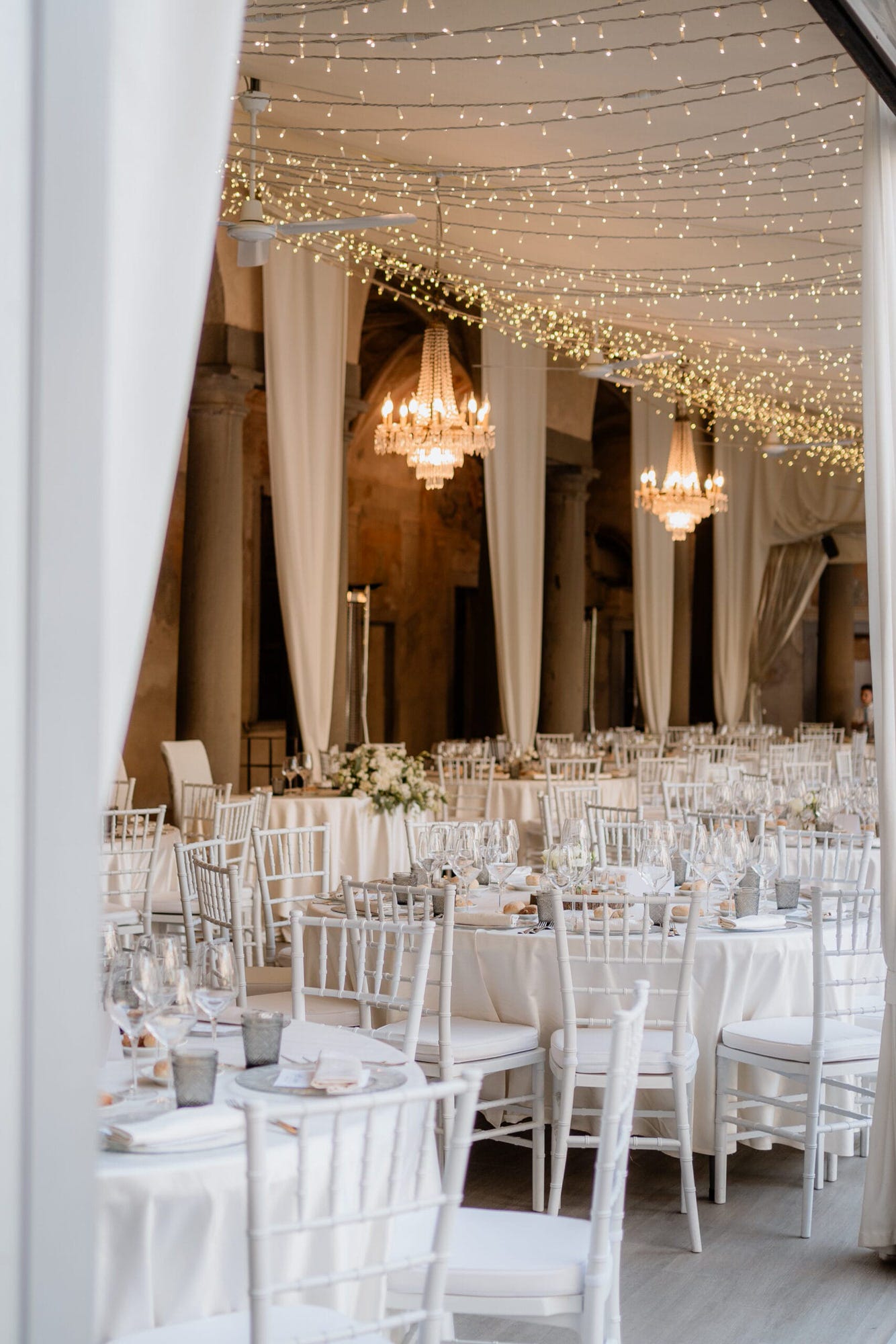 Un'immagine elegante della cena del matrimonio al Castello di Cavernago, Bergamo, dove gli sposi e gli invitati si deliziano con piatti prelibati, immersi nell'atmosfera romantica e raffinata della location.